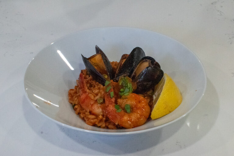 pescatarian paella in a Dutch oven on a Weber kettle grill