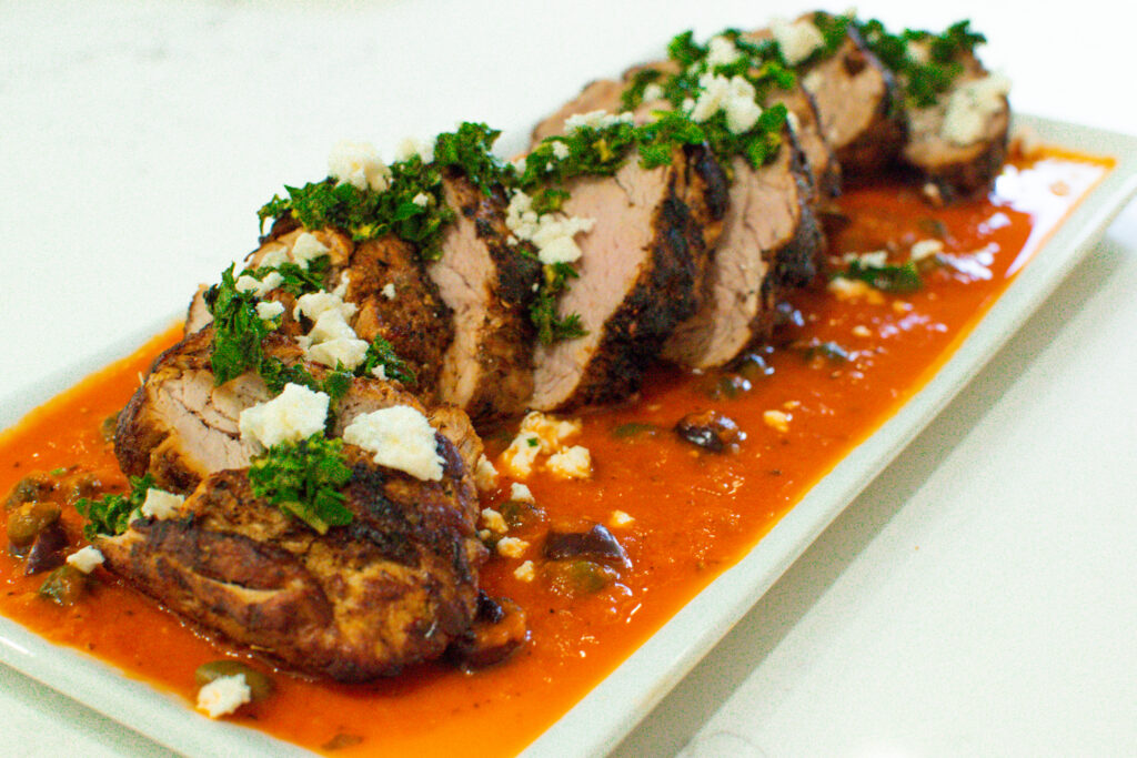 mediterranean pork tenderloin sliced over roasted red pepper sauce with herb gremolata