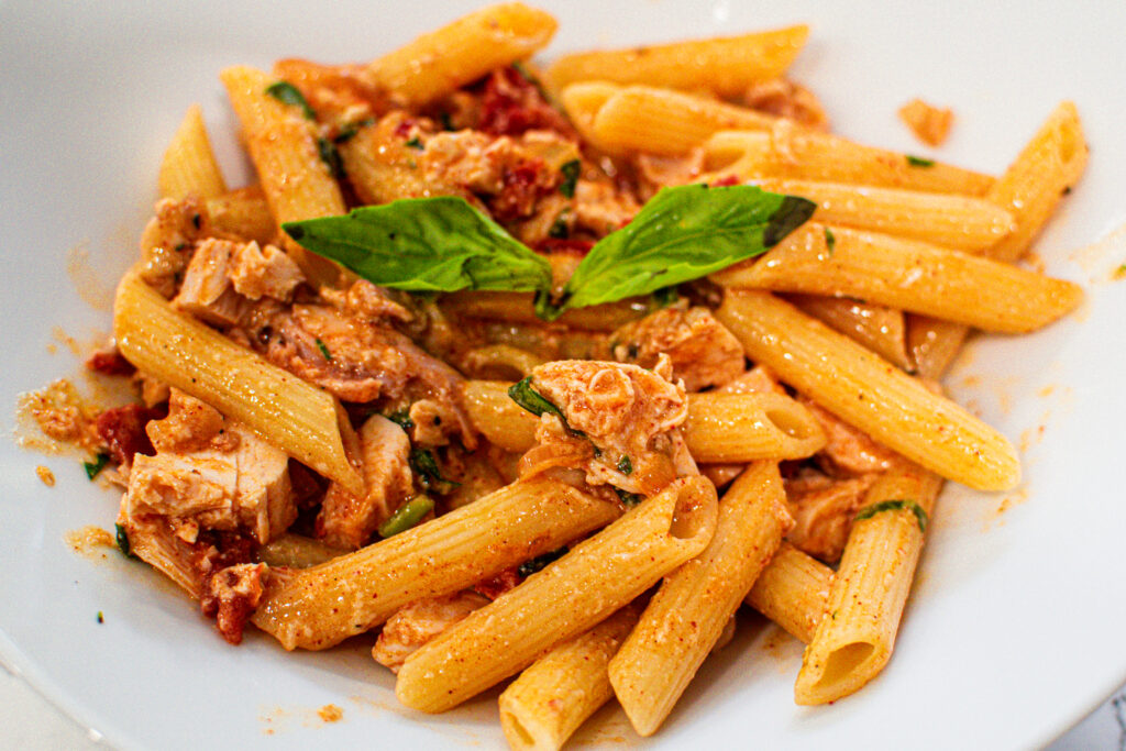 smoky beer can chicken penne pasta in a skillet with parmesan and fresh basil